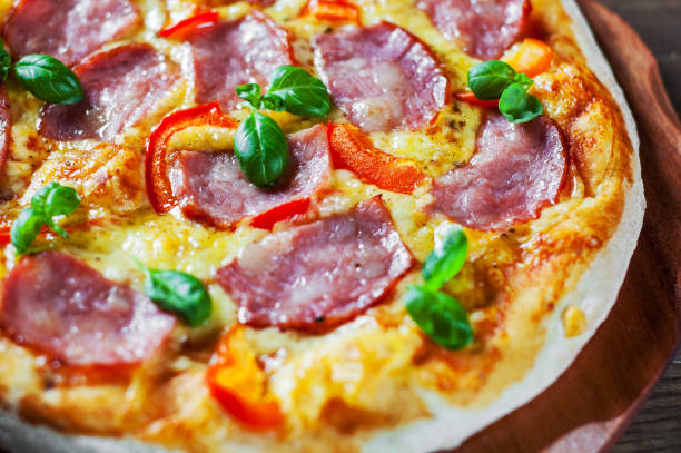 istock Pizza with Mozzarella cheese, ham, pepper, meat, Tomato sauce, Spices and Fresh Basil. Italian pizza on wooden background 1095282938