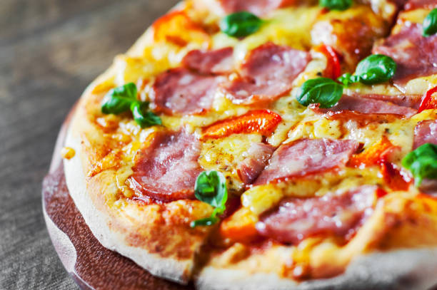 istock Pizza with Mozzarella cheese, ham, pepper, meat, Tomato sauce, Spices and Fresh Basil. Italian pizza on wooden background 1095282966
