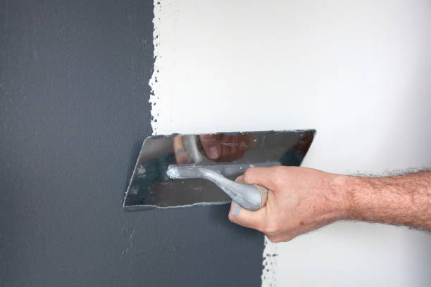 Plastering of a Concrete Wall Hand with a trowel plastering a wall with decorative plaster hand with a plaster spatula stock pictures, royalty-free photos & images