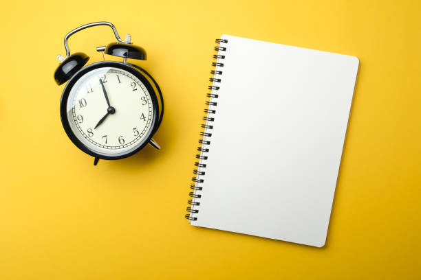 istock black alarm clock with blank white notebook on yellow background color 1095285914