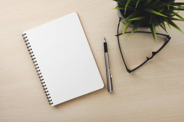 istock Empty white notebook top view on wood table close to pen and glasses 1095286354