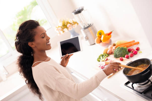 istock Kitchen woman following recipe online while stirring the soup. 1095286362
