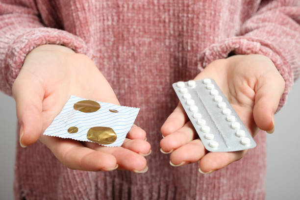 oral contraceptive pills and condom Woman holding in hands oral contraceptive pills and condom, choice. Concept gynecology, sex education. condom photos stock pictures, royalty-free photos & images