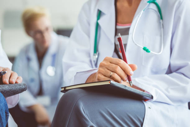 Close up of female medical professional making notes during seminar. Doctor writing notes in diary during healthcare conference.