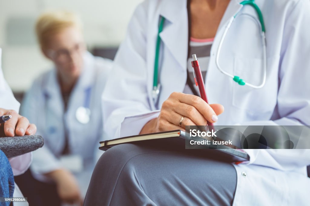 Female doctor making notes during seminar Close up of female medical professional making notes during seminar. Doctor writing notes in diary during healthcare conference. Healthcare And Medicine Stock Photo