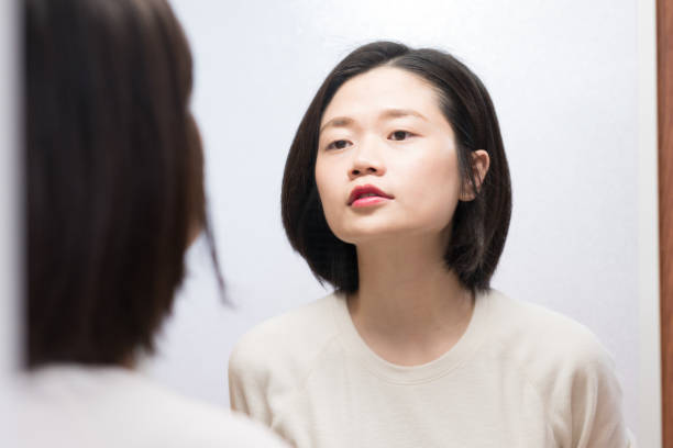 istock asian female looking in mirror 1095298944