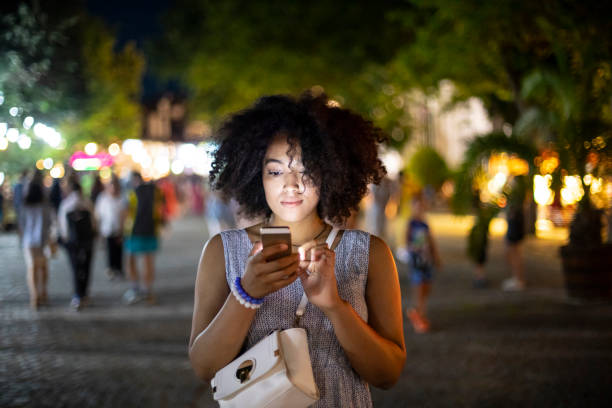 Smiling african woman using smart phone on street