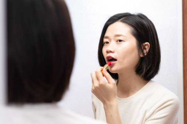 istock asian female applying makeup and looking in mirror 1095302500