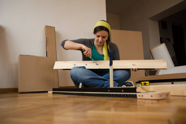istock Women in her new apartment assembling flat pack furniture - Image 1095307532