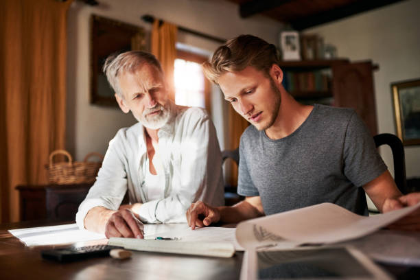 Let's go over it together Shot of two men working on a project together at home college student and parent stock pictures, royalty-free photos & images