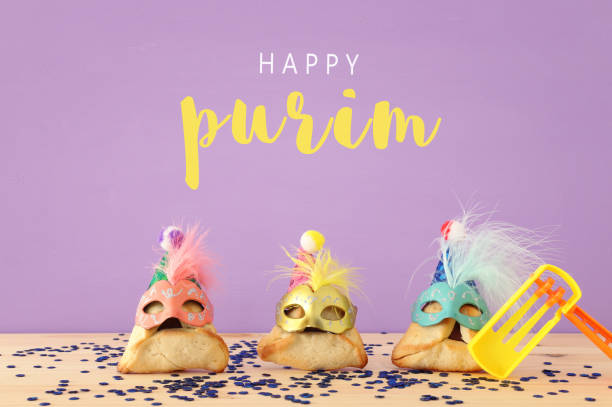 Purim celebration concept (jewish carnival holiday). Traditional hamantaschen cookies with cute clown hats and masks over wooden table. Purim celebration concept (jewish carnival holiday). Traditional hamantaschen cookies with cute clown hats and masks over wooden table religious celebration audio stock pictures, royalty-free photos & images