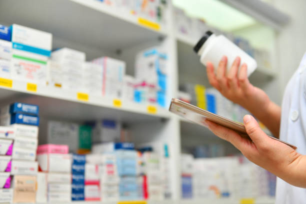 istock Pharmacist holding medicine bottle and computer tablet 1095337076