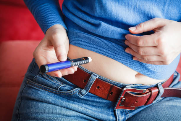 mujer realiza inyección de insulina en el estómago - insulin fotografías e imágenes de stock