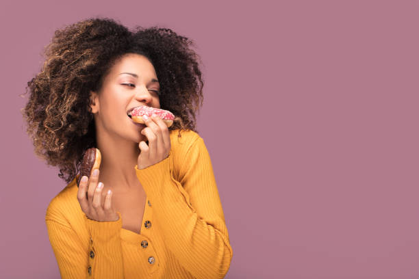 istock Young afro woman eating donuts. 1095354556