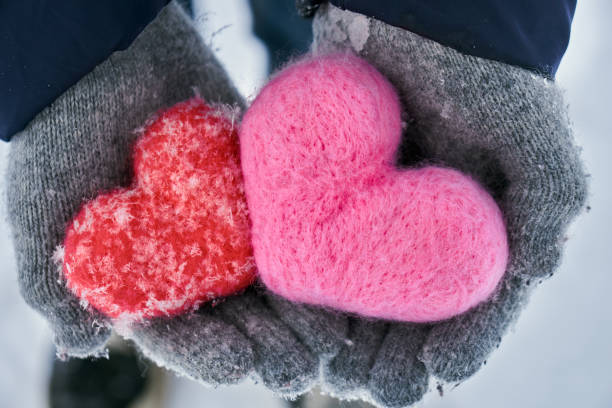istock Hands in wollen gloves holding two woolen hearts covered with snowflakes 1095363744