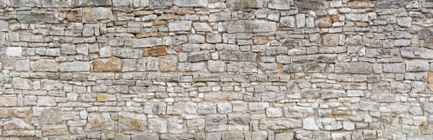 Old gray natural stone wall Panorama - Old gray wall of rough, many small, rectangular hewn natural stones fortified wall stock pictures, royalty-free photos & images