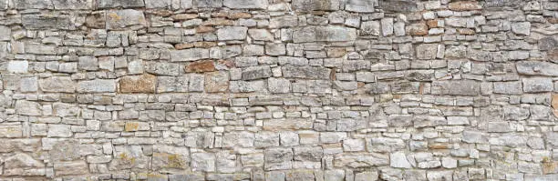 Panorama - Old gray wall of rough, many small, rectangular hewn natural stones