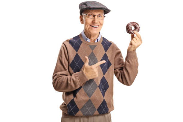 istock Cheerful senior man holding a chocolate donut and pointing at it 1095371934