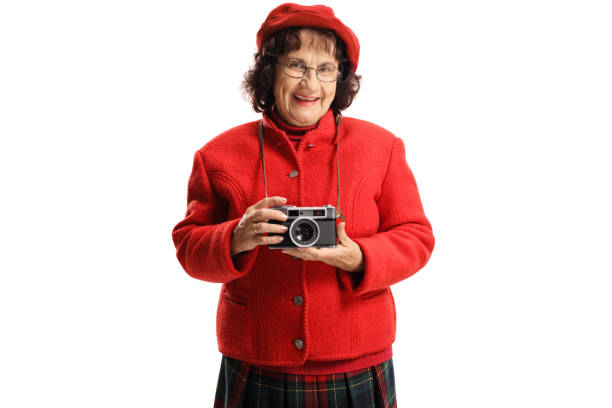 Smiling old lady with a vintage camera isolated on white background