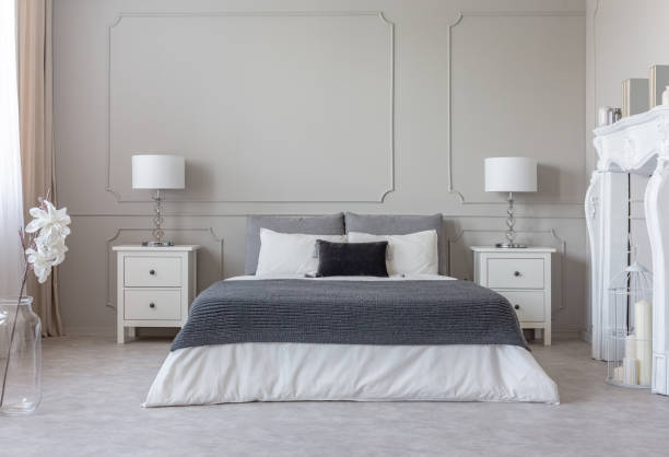 istock Grey blanket on white bedding on comfortable king size bed, two nightstand with lamps on both sides of it 1095372304