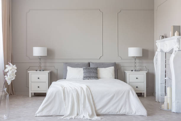 istock White wooden fireplace portal in bright bedroom interior, copy space on empty grey wall 1095372312