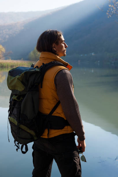 istock Man with backpack standing by the lake landscape 1095372606