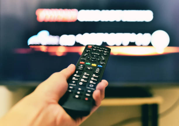 istock Remote TV / Watching TV and using remote controller in hand home theater entertainment 1095372814