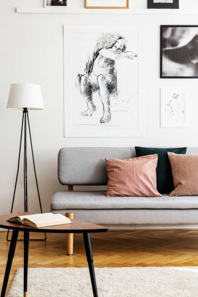 istock Book on table in front of couch with pillows in bright loft interior with lamp and posters. Real photo 1095373106