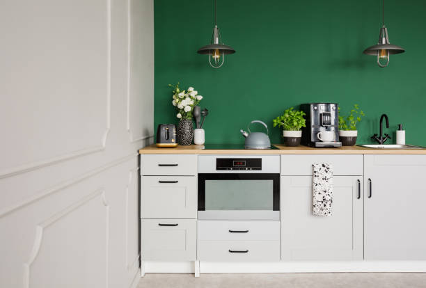 istock Empty green wall with copy space in elegant kitchen with white furniture,plants and coffee machine 1095377750