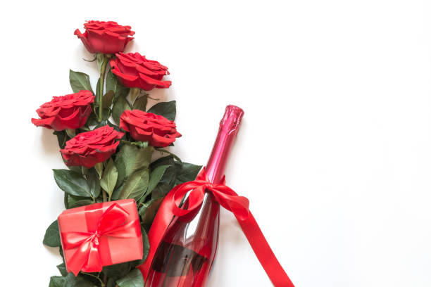 Two champagne glasses with red heart shaped confetti splash over white background. Valentine's Day concept