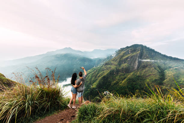 A couple in love is photographed on the phone. Boy and girl in the mountains. Man and woman holding hands. The couple travels around Asia. Travel to Sri Lanka. Serpentine in the mountains. Lover stock photo