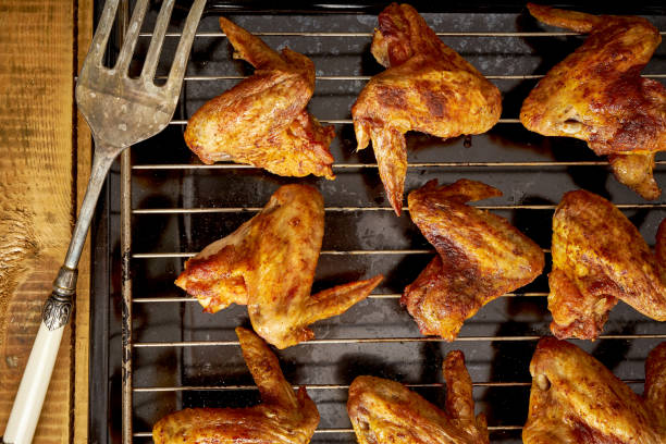 istock Delicious hot grilled chicken wings on grid grill with a fork. 1095378488