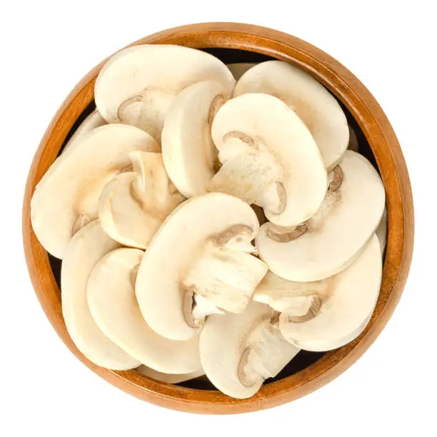 Photo of Sliced white champignon mushrooms in wooden bowl