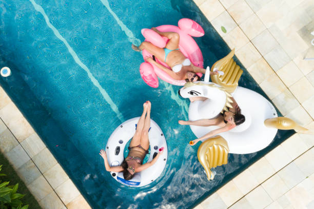 amigos que se divierten con flotador inflable en piscina - vista aérea - heat mid air flying float fotografías e imágenes de stock
