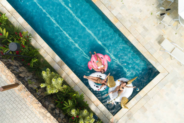 amigos que se divierten con flotador inflable en piscina - vista aérea - heat mid air flying float fotografías e imágenes de stock