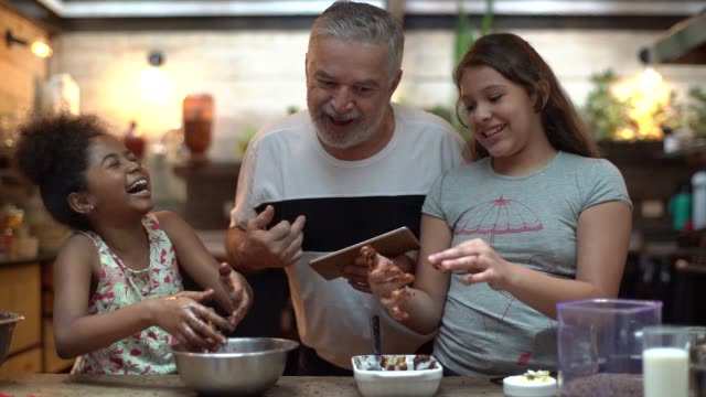 Hispanic-latino grandfather teaching their grandchild how to cook at home - They are preparing Brazilian Brigadeiro