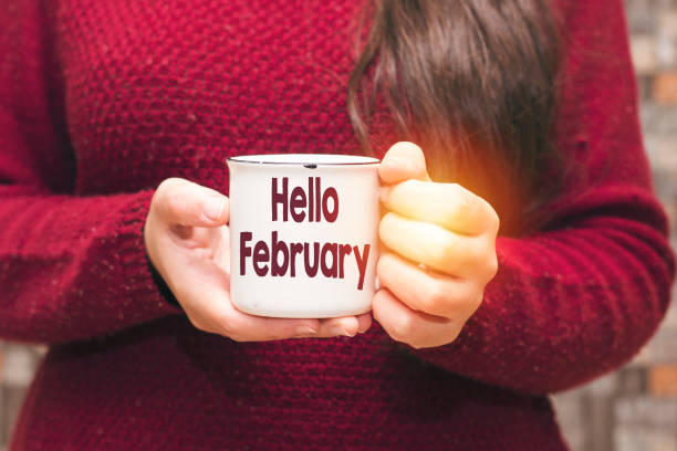 istock hello february text on cup and woman drinking a coffee 1095412596