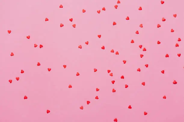 Photo of Valentine's day background. Little red hearts on pink background.