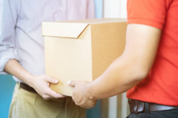 istock parcel delivery man of a package through a service. and close up hand customer accepting a delivery of boxes from delivery man postal send direct to home. 1095421640