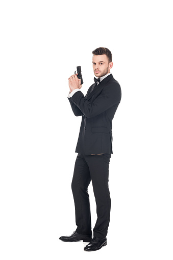 elegant secret agent in black suit holding gun, isolated on white