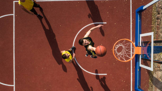 Basketball player making Slam dunk Basketball player scoring with slam dunk, drone point of view, outdoor team sport photos stock pictures, royalty-free photos & images