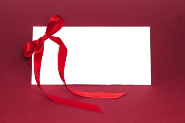 istock Gift isolated white card with red ribbon bow on deep red background. 1095425550