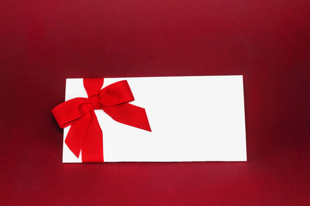 istock Isolated white gift card with red ribbon bow on deep red background. 1095425556