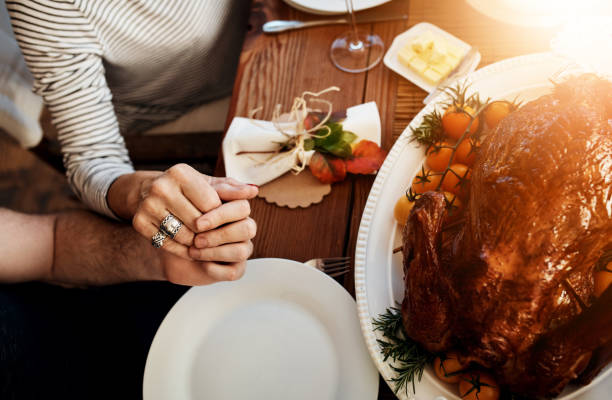 Find reasons to give thanks High angle shot of an unrecognizable family saying grace at the dining table on Thanksgiving saying grace stock pictures, royalty-free photos & images