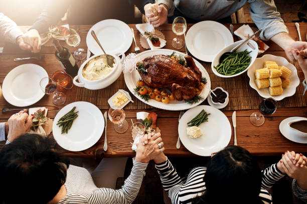 Turkey sure is the center piece of every meal High angle shot of an unrecognizable family saying grace at the dining table on Thanksgiving saying grace stock pictures, royalty-free photos & images