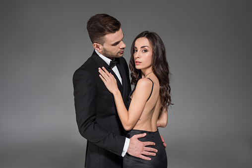 attractive elegant couple in black clothes hugging isolated on grey