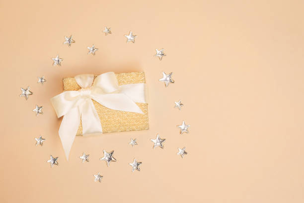 istock Sparkling golden present box on pastel background decorated with shiny silver stars. Copy space. 1095433444