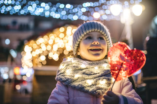 Beautiful carefree smiling child on a New year's eve Lovely and beautiful toddler girl enjoying her time outdoors in the city during Christmas holidays. christmas market photos stock pictures, royalty-free photos & images