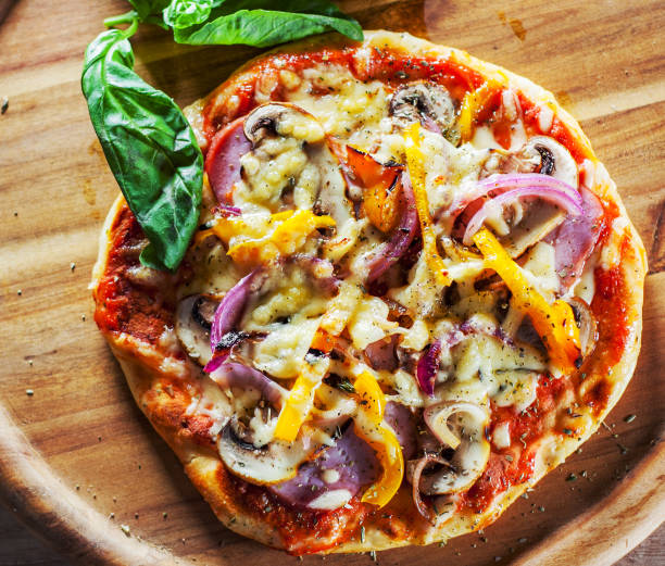 Greek pizza with mushrooms, ham, cheese, onions, pepper on wooden board Greek pizza with mushrooms, ham, cheese, onions, pepper on wooden board pita bread stock pictures, royalty-free photos & images
