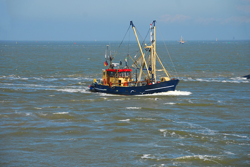 Wadden sea:  : A fishing vessel ( cutter) with waves at the bow. On board is a commercial fishing net.